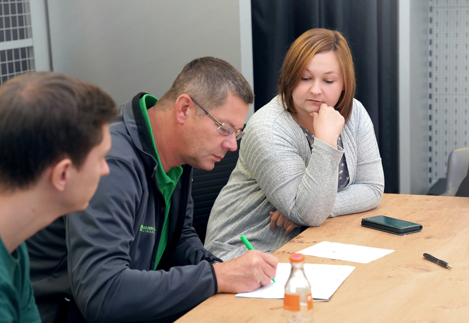 3 Personen sitzen an einem Tisch